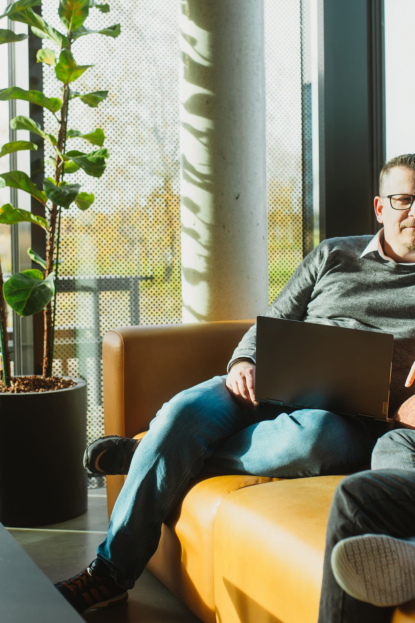 Zwei Kollegen besprechen IT-Management mit einem Laptop in einer hellen Lounge.